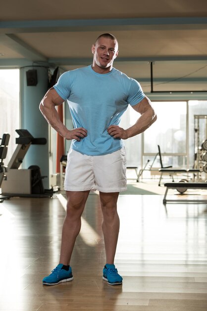 Serious Man Standing In The Gym And Flexing Muscles In TShirt