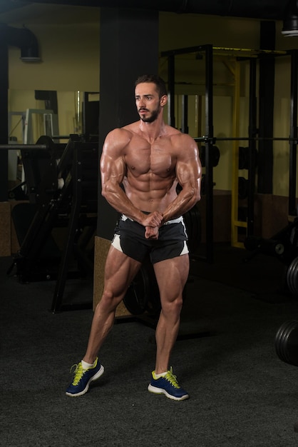 Serious Man Standing Strong In The Gym And Flexing Muscles