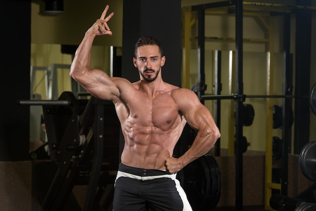 Serious Man Standing Strong In The Gym And Flexing Muscles