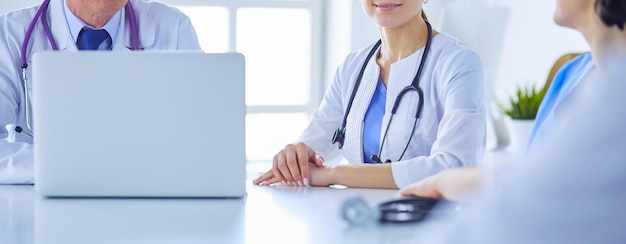 Serious medical team using a laptop in a bright consulting room