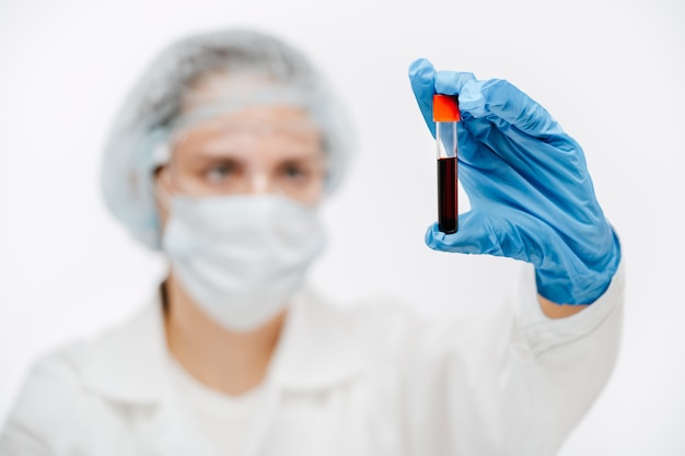 Serious medical worker in color gloves holding tube of blood sample in clini