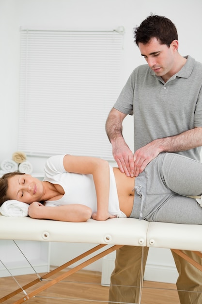 Serious physiotherapist checking the pelvis of a woman