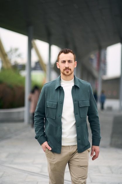 Serious professional businessman looking at camera and walking at the street