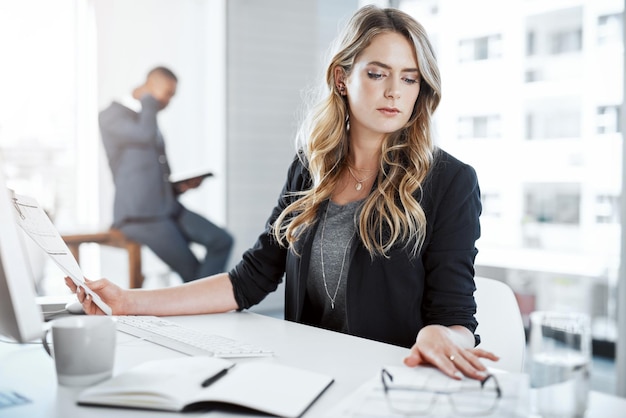 Serious reading and woman in office paperwork and thinking of research notes and journalist on desk Company digital and reporter with notebook for editing of story for blog news and press