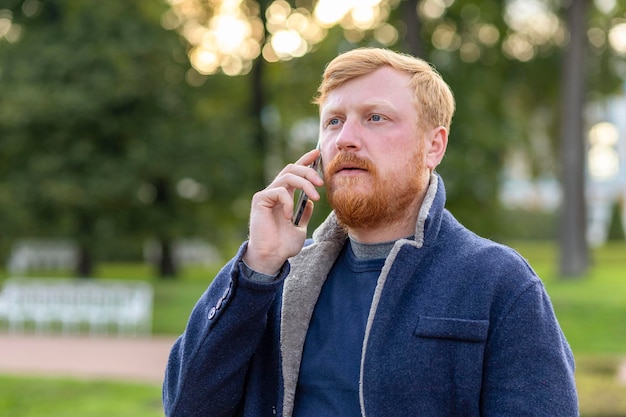 Serious red haired businessman. man beard, mustache talking smartphone, mobile. stylish ginger bearded freelancer guy using phone