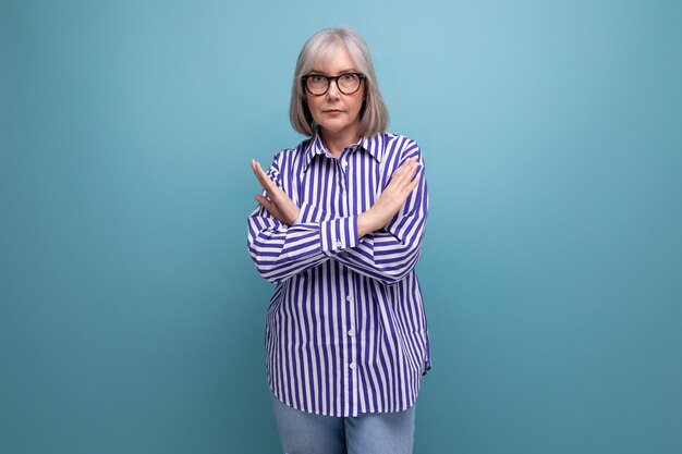 Serious s middleaged woman with gray hair in a fashionable shirt on a bright studio background with