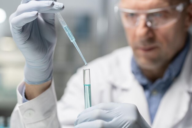 Serious scientist with flask and pipette making experiment with liquid substance