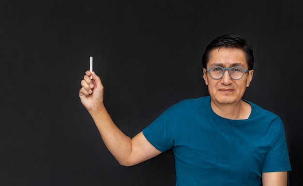 Serious teacher dictates his class with chalk on a blackboard