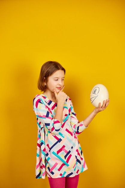 Serious teenager girl holding Ostrich egg with funny face