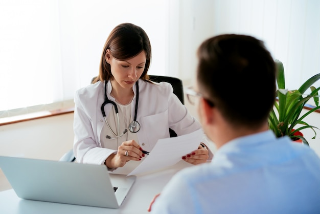 Serious woman doctor in pharmacy reading medical prescription to patient