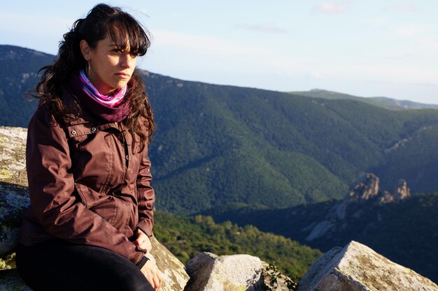 Photo serious woman on the hill of a mountain contemplating the landscape