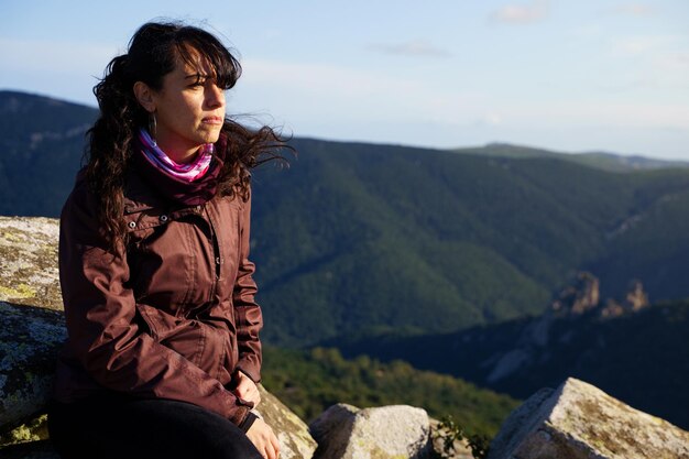 Photo serious woman on the hill of a mountain looking the landscape