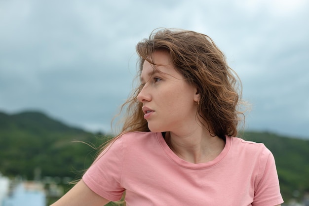 Serious woman looks away on the street against the backdrop of mountains depressed or upset in bad weather