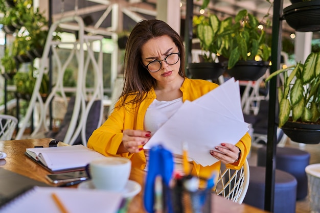 Serious woman working in the office in glasses and notebook