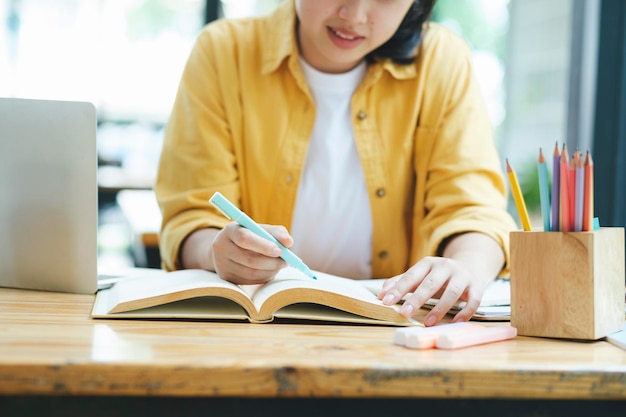 Serious young asian student reading a book preparing the exam