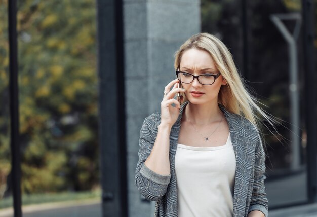 Serious young attractive business woman talking on the phone against the background of a business office. Bad news