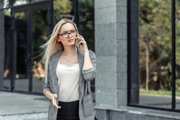 Serious young attractive business woman talking on the phone against the background of a business office. Bad news