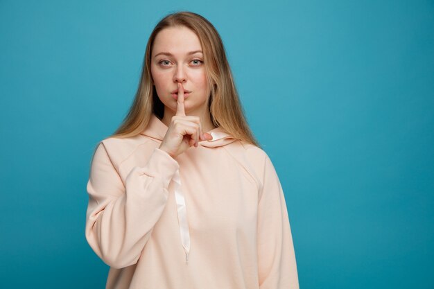 Serious young blonde woman doing silence gesture 