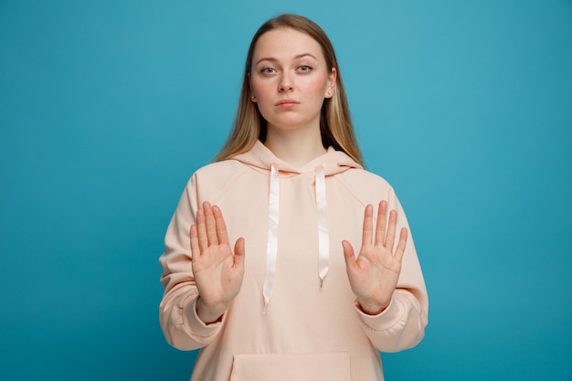 Serious young blonde woman doing stop gesture 