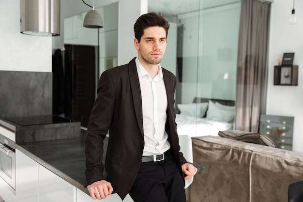 Serious young businessman standing in home