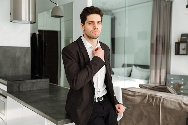 Serious young businessman standing in home