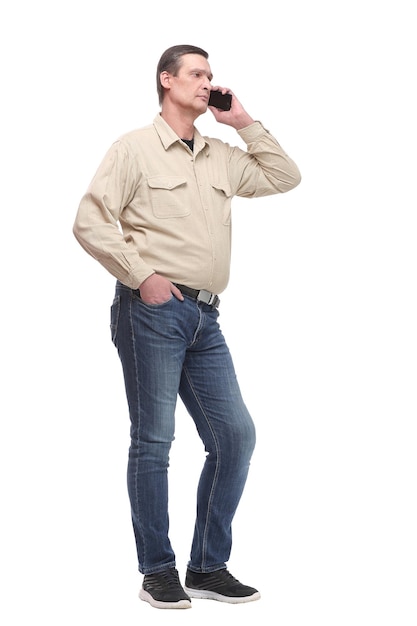 Serious young casual man standing with a hand in his pocket and speaking on the phone