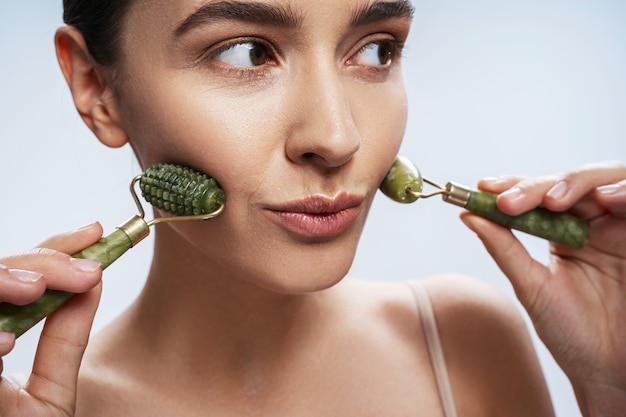 Serious young caucasian woman massaging her facial skin