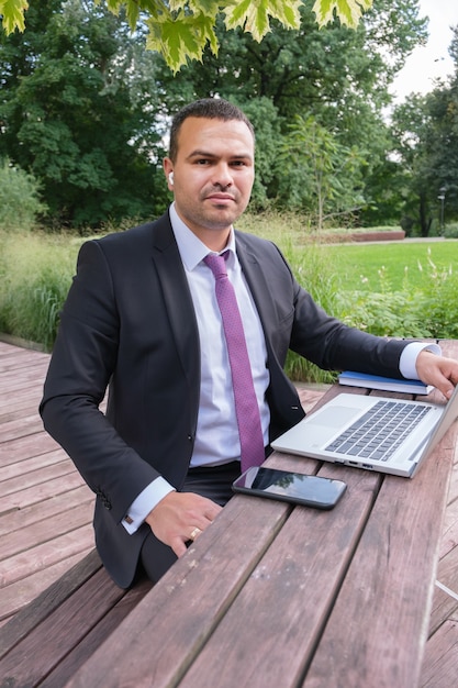 Serious young man in business suit and tie works on open veranda