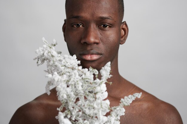 Serious young man with blooming branch looking at you