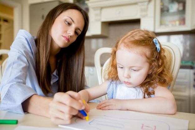 Serious young woman drawing together with daughter