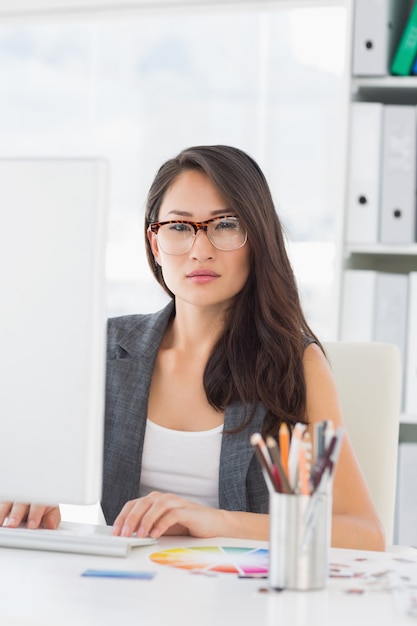 Serious young woman using computer in office