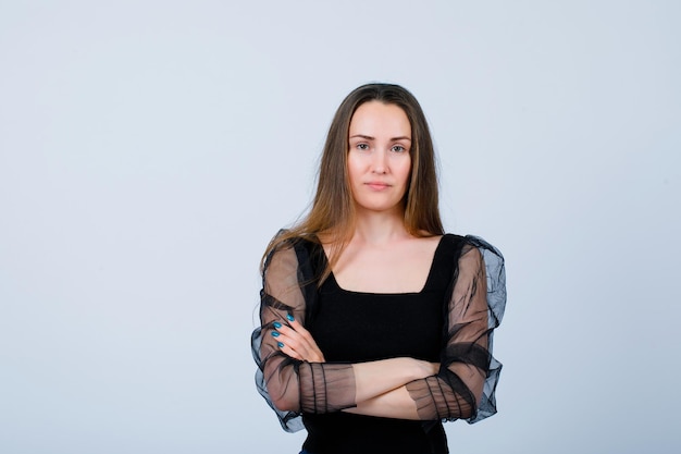 Seriously girl is looking at camera by crossing arms on white background