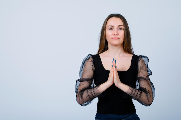 Seriously girl is looking at camera by holding hands together on white background