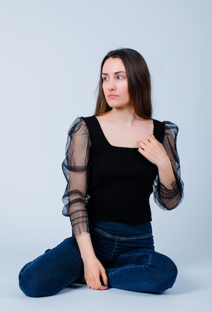 Seriously girl is looking left by sitting on floor on white background