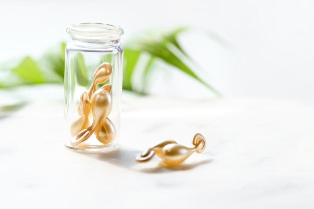 Serum capsules for healthy skin Closeup on transparent bottle with the capsules Green palm leaf