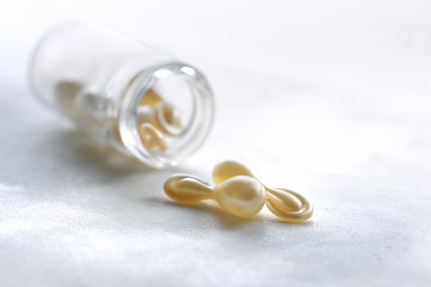 Serum capsules for healthy skin Closeup on transparent bottle with metallic golden capsules