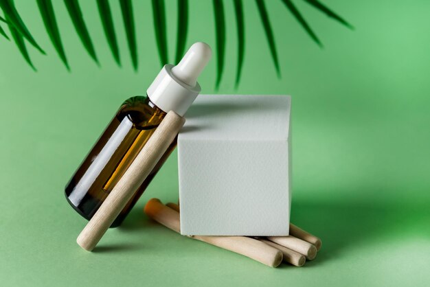 Serum Cosmetic Bottle with Peptides and Retinol Platform Pedesta and Wooden Sticks Green Background