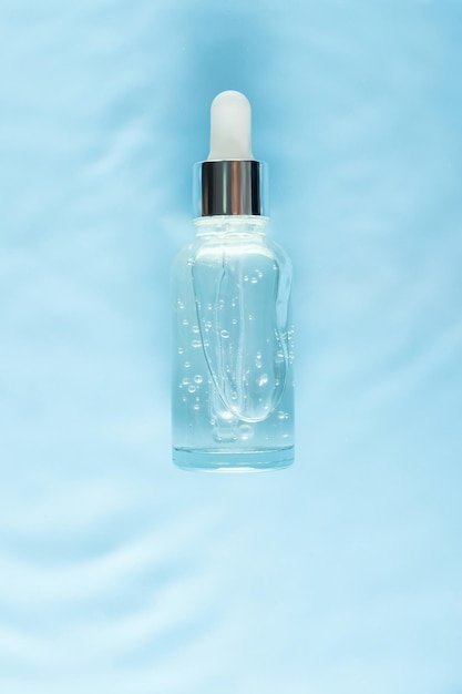 Serum glass bottle on water with drops Concept of moisturizing cosmetics with natural marine collagen Skin care antiaging