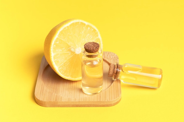 Serum with vitamin C Lemon essential oil Glass bottle with a pipette half a lemon on yellow background Health and beauty concept Organic natural cosmetics