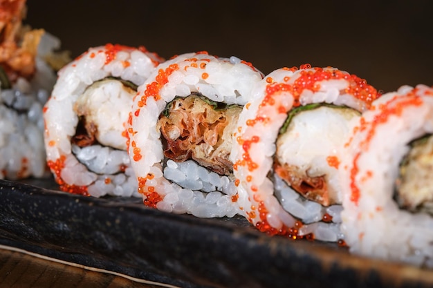 Served delicious set of Japanese uramaki sushi with red tobiko roe on plate