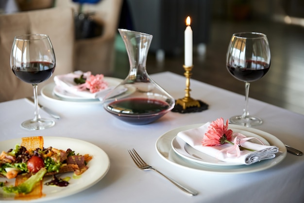 A served restaurant table with glasses of red wine and appetizer awaits guests