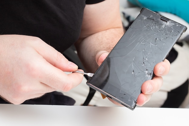 Service center for the repair of mobile phones. The wizard removes the screen protective glass from a smartphone