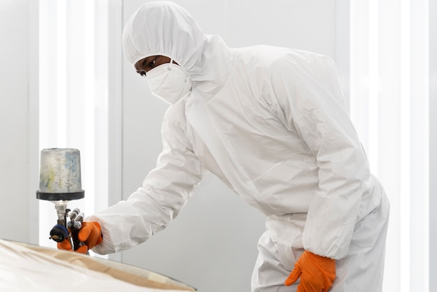 Service worker painting car in auto service