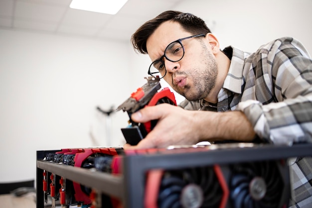 Serviceman cleaning up dust from graphics card in bitcoin mining rig