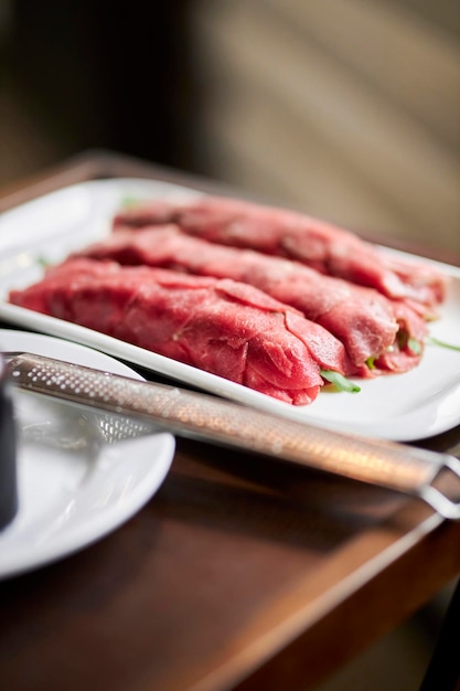 Serving carpaccio. The chef burns the carpaccio with a burner. Carpaccio. Meat in the restaurant