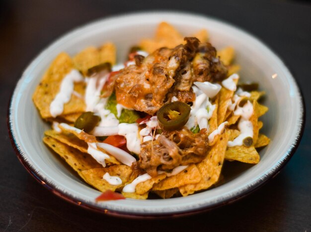 Serving of nachos with meat cheese white sauce and jalapenos