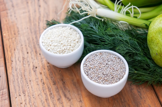 Sesame, chia seeds with dill and green onions. Healthy vegan food on wooden background.