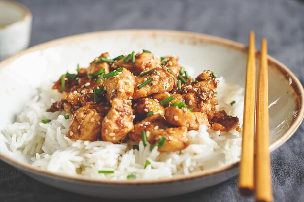 Sesame chicken pieces with rice on a ceramic plate Chinese traditional dish