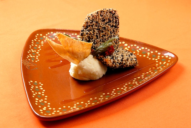 sesame covered salmon fillet with mashed potatoes and tortilla chips, clay dish, mexican food