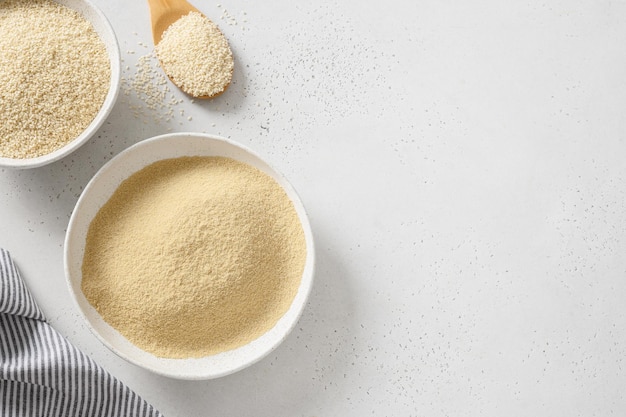 Sesame flour in wooden spoon on white